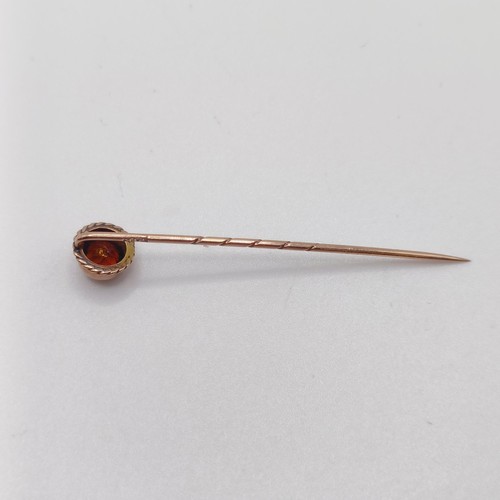 596 - An early 20th century yellow coloured metal and orange stone stick pin  Provenance:  From a single o... 