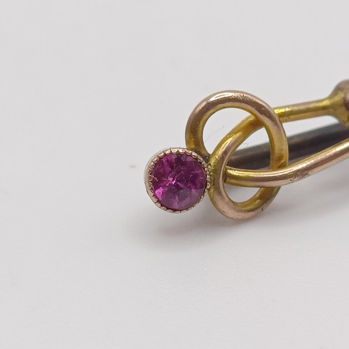 595 - A late 19th/early 20th century yellow coloured metal and amethyst stick pin, in the form of a knot P... 