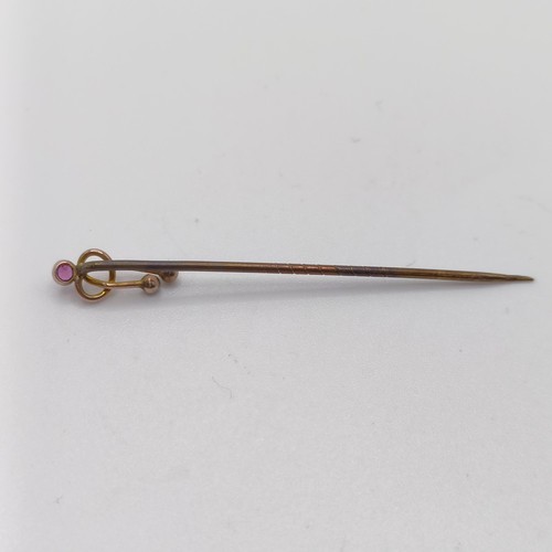 595 - A late 19th/early 20th century yellow coloured metal and amethyst stick pin, in the form of a knot P... 