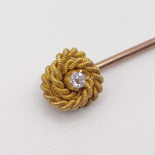 594 - A late 19th/early 20th century yellow coloured metal and diamond stick pin, in the form of a knot Pr... 