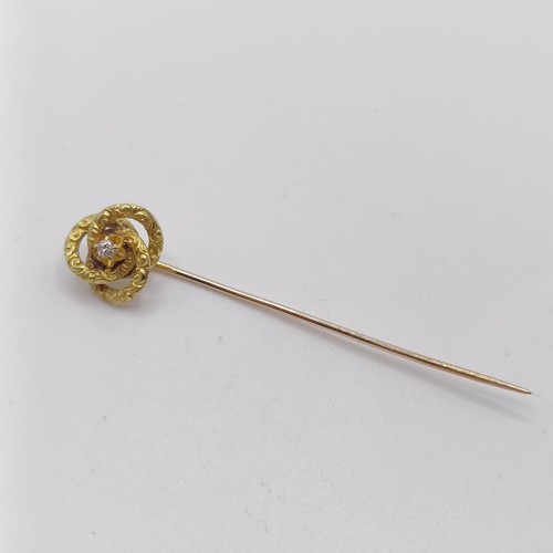 592 - A yellow coloured metal and diamond stick pin, in the form of a knot  Provenance:  From a single own... 