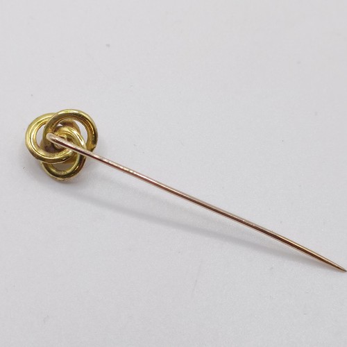 592 - A yellow coloured metal and diamond stick pin, in the form of a knot  Provenance:  From a single own... 