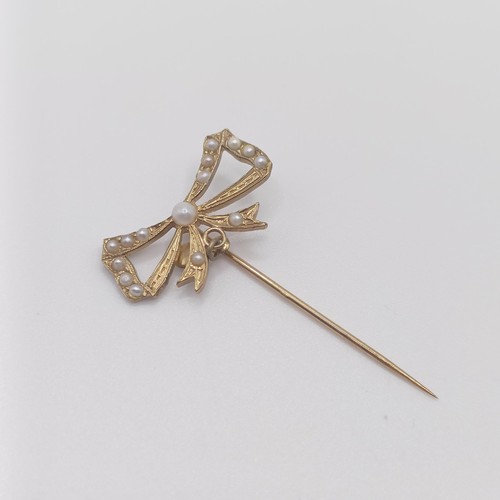 589 - An early 20th century 9ct gold and seed pearl stick pin, in the form of a bow  Provenance:  From a s... 