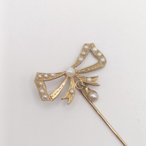 589 - An early 20th century 9ct gold and seed pearl stick pin, in the form of a bow  Provenance:  From a s... 