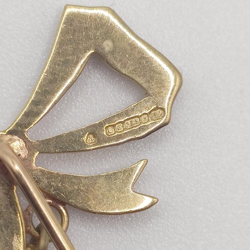 589 - An early 20th century 9ct gold and seed pearl stick pin, in the form of a bow  Provenance:  From a s... 