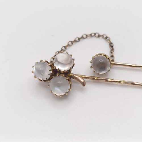 582 - A late 19th/early 20th century yellow metal and moonstone double stick pin, linked with a chain Prov... 