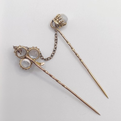 582 - A late 19th/early 20th century yellow metal and moonstone double stick pin, linked with a chain Prov... 