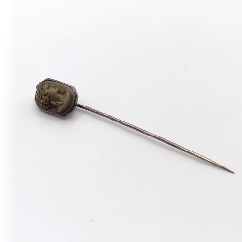 555 - A 20th century silver coloured metal stick pin, inset with lava stone cameo, decorated lady   Proven... 