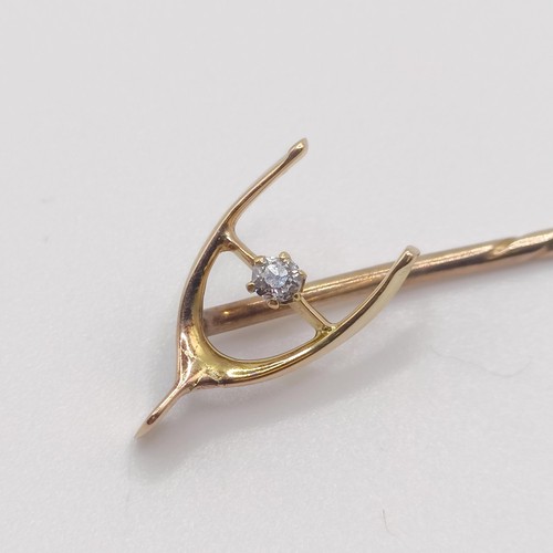 550 - A late 19th/early 20th century yellow metal and diamond stick pin, in the form of a wishbone  Proven... 