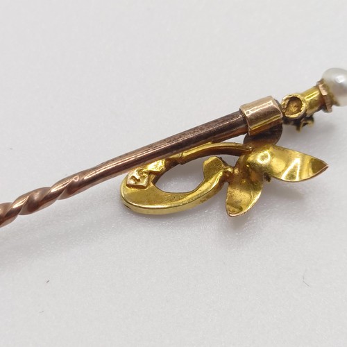 546 - An early 20th century yellow coloured metal and multi-coloured stone stick pin, in the form of a flo... 