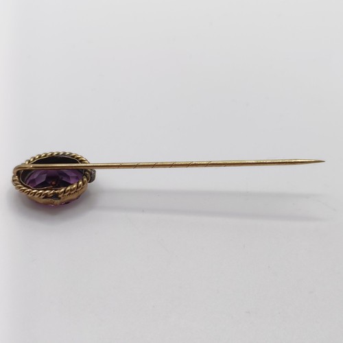 542 - A late 19th/early 20th century yellow metal and engraved purple stone stick pin  Provenance:  From a... 