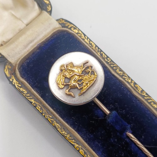 518 - An early 20th century yellow metal and silver stick pin, decorated George slaying the Dragon, in a v... 