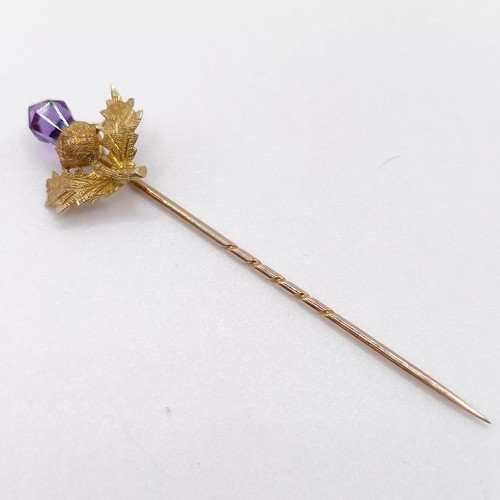 656 - A late 19th/early 20th century yellow metal and amethyst stick pin, in the form of a thistle  Proven... 