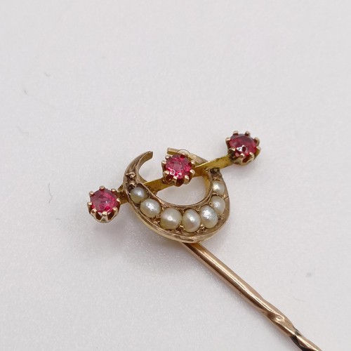 653 - A late 19th/early 20th century yellow metal, seed pearl and red stone stick pin, in the form of a cr... 