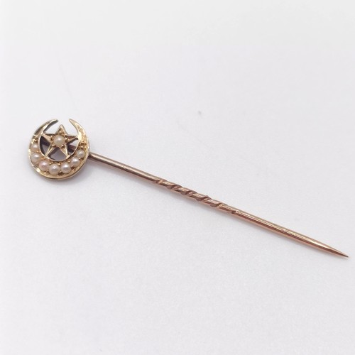 651 - A late 19th/early 20th century yellow metal and seed pearl stick pin, in the form of a crescent moon... 