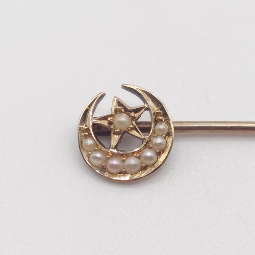 651 - A late 19th/early 20th century yellow metal and seed pearl stick pin, in the form of a crescent moon... 