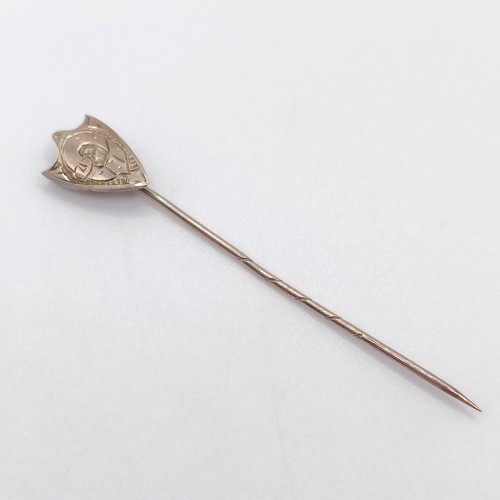 650 - A yellow coloured metal stick pin, in the form of a shield   Provenance:  From a single owner collec... 