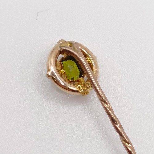 646 - An early 20th century yellow coloured metal and peridot stick pin  Provenance:  From a single owner ... 