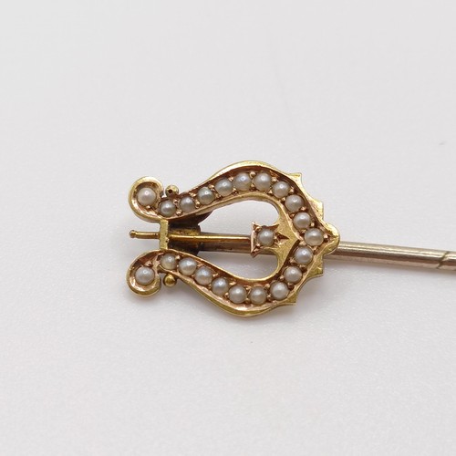 637 - A late 19th/early 20th century yellow coloured metal and seed pearl stick pin, in the form of a harp... 