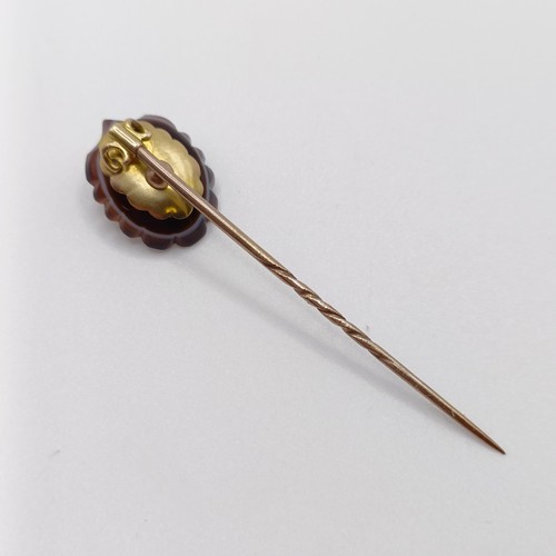 612 - A late 19th/early 20th century yellow coloured metal, carved hardstone and pearl stick pin, in the f... 