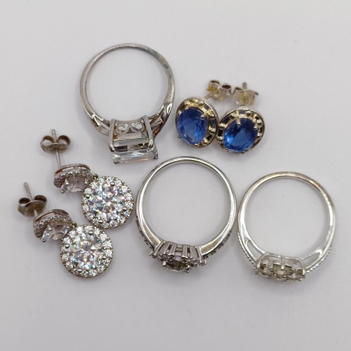 926 - A silver and white stone dress ring, ring size S, two other rings, and two pairs of earrings