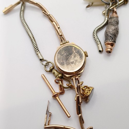 846 - A ladies 9ct gold wristwatch, a charm, a novelty whistle, in the form of an owl, on a silver plated ... 