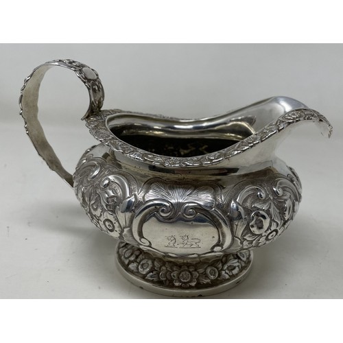 1094 - A George III silver cream jug, crested, with embossed decoration, 8.70 ozt