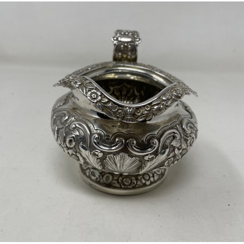 1094 - A George III silver cream jug, crested, with embossed decoration, 8.70 ozt