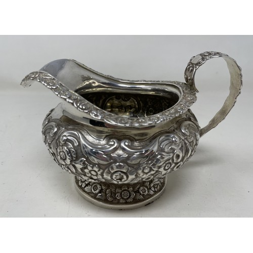 1094 - A George III silver cream jug, crested, with embossed decoration, 8.70 ozt