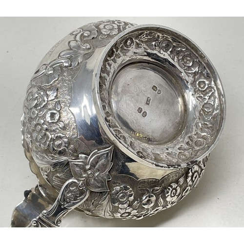 1094 - A George III silver cream jug, crested, with embossed decoration, 8.70 ozt