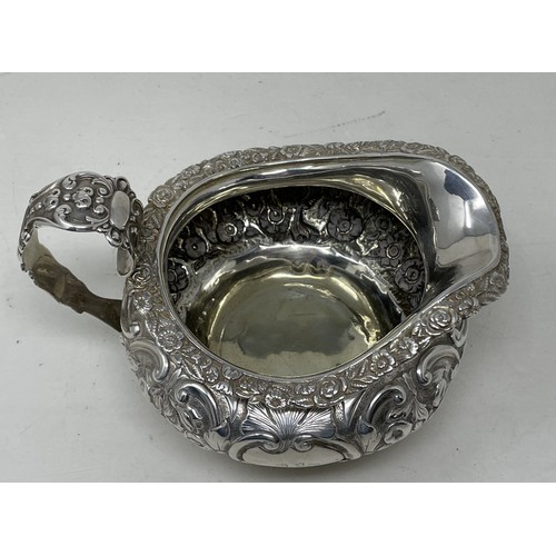 1094 - A George III silver cream jug, crested, with embossed decoration, 8.70 ozt