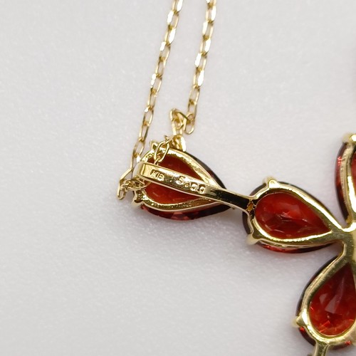 673 - An 18ct yellow gold cross necklace, set with 5.00ct pear shaped garnets, boxed