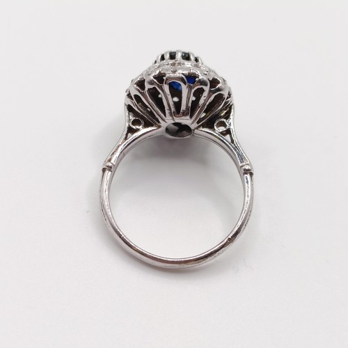 815 - An Eastern white metal ring, with oval sapphire and double halo of rose cut diamonds