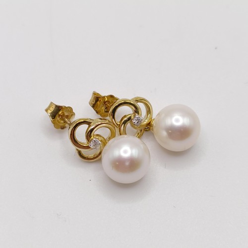 717 - A pair of 9ct yellow gold, round freshwater pearl and diamond pinwheel earrings, boxed