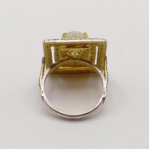 787 - A large rectangular silver gilt dress ring, set with an oval cabochon white opal and rose cut diamon... 