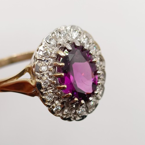 816 - A 9ct yellow and white gold dress ring, set with a purplish red rhodolite garnet, and an R/C diamond... 