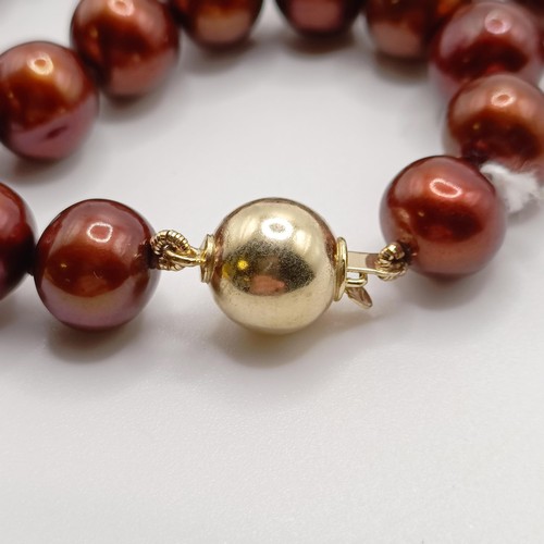 719 - A string of cocoa freshwater cultured pearls, with a 9ct yellow gold ball clasp