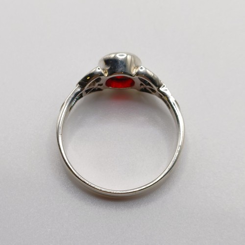 718 - A silver celtic style ring, set with an oval red CZ