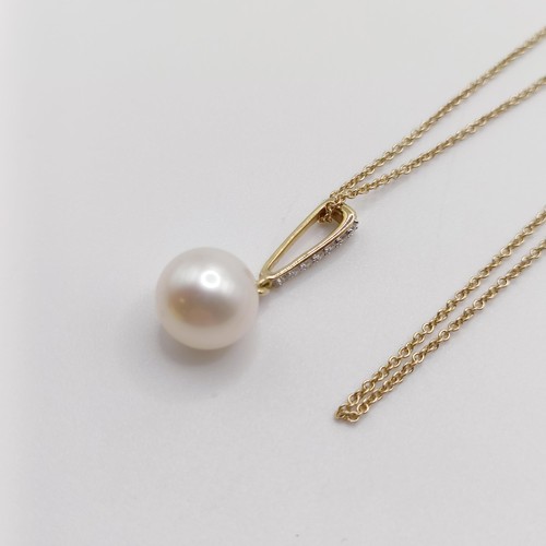 720 - A 9ct yellow gold, round freshwater pearl and diamond pendant, on a 9ct yellow gold chain, boxed