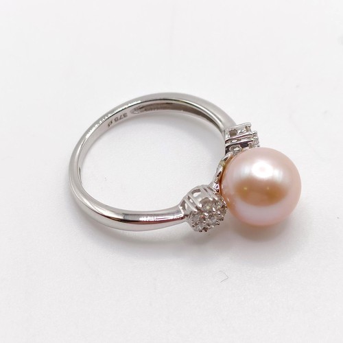 734 - A 9ct white gold ring, set with round peach cultured pearl flanked by daisy clusters of R/C diamonds