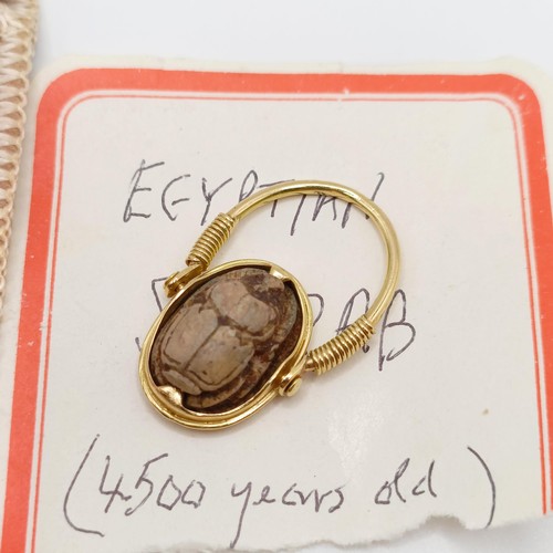 855 - A yellow coloured metal hinged ring, inset with a scarab, the undersigned with hieroglyphics, ring s... 