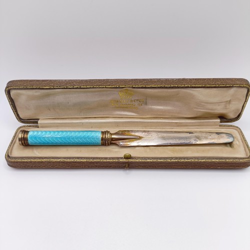 868 - A 1920s yellow and silver coloured metal and blue enamel paperknife, in a fitted case, retail mark f... 