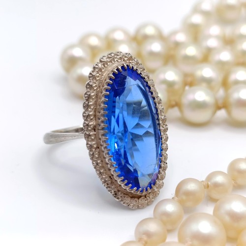 974 - A silver, white and blue stone dress ring, two other rings, and a simulated pearl necklace