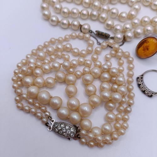 974 - A silver, white and blue stone dress ring, two other rings, and a simulated pearl necklace