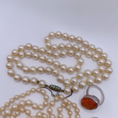 974 - A silver, white and blue stone dress ring, two other rings, and a simulated pearl necklace