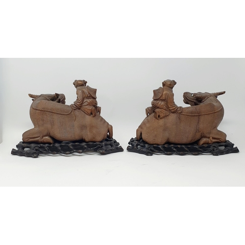 1451A - A pair of Chinese carvings of oxen, with figures on their backs, on pierced stands, 25 cm wide (2)