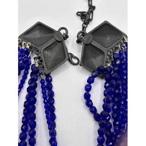 581 - A Jean Paul Gaultier blue bead triple thread necklace, with a cross pendant