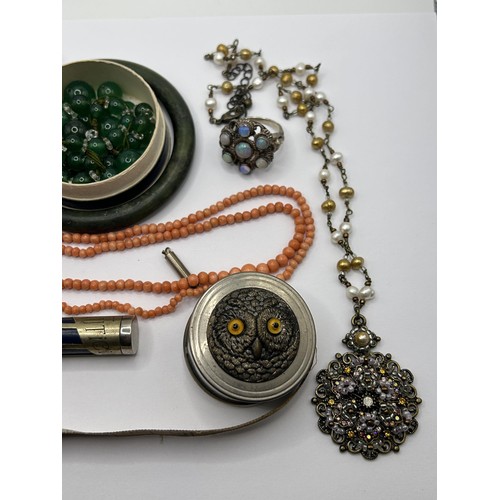 629 - A carved green stone bangle, a coral necklace, a novelty tape measure, decorated owl, and other item... 