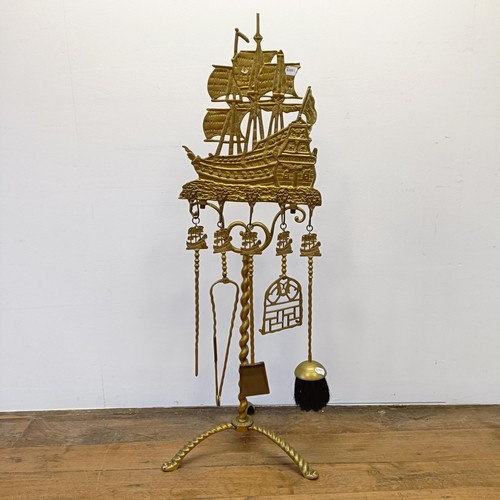 987 - A Dutch brass fire companion set, the stand with a large galleon finial, 120 cm high