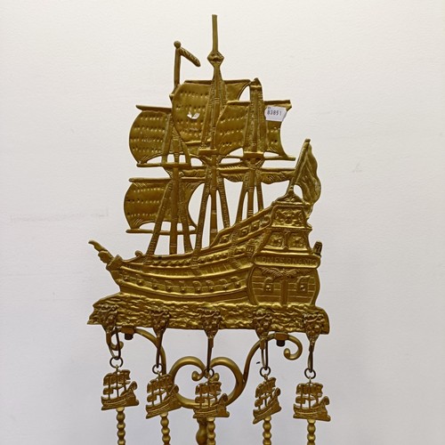 987 - A Dutch brass fire companion set, the stand with a large galleon finial, 120 cm high